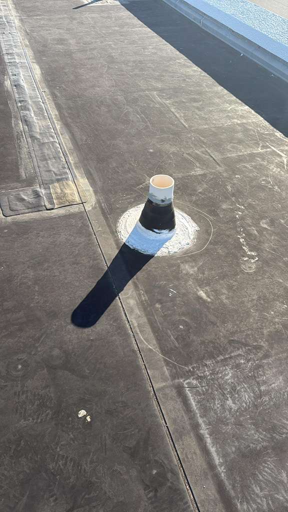 Sealed pipe boot on a flat commercial roof